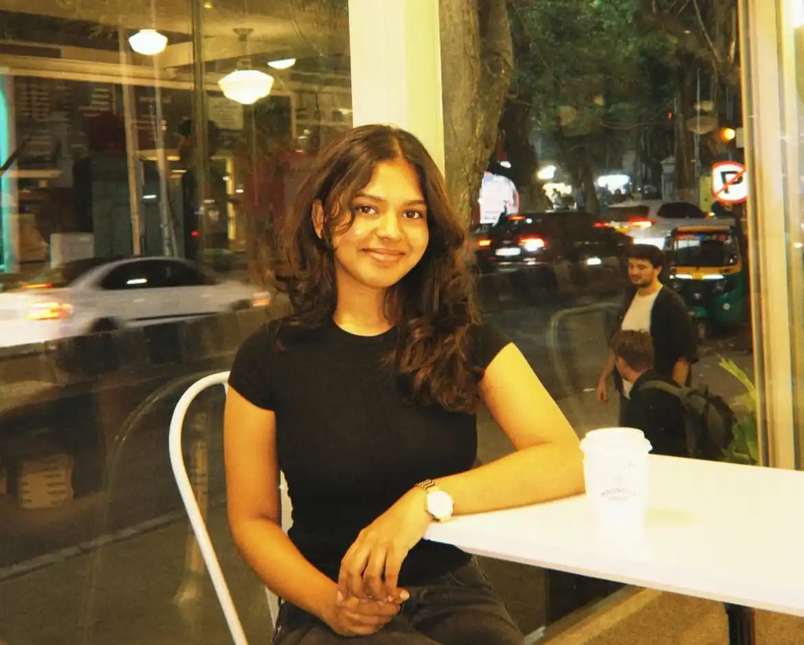Portrait of a satisfied client sitting at a café table with a takeaway coffee cup, featured in a testimonial for a Digital Marketing Consultant in Bahrain.