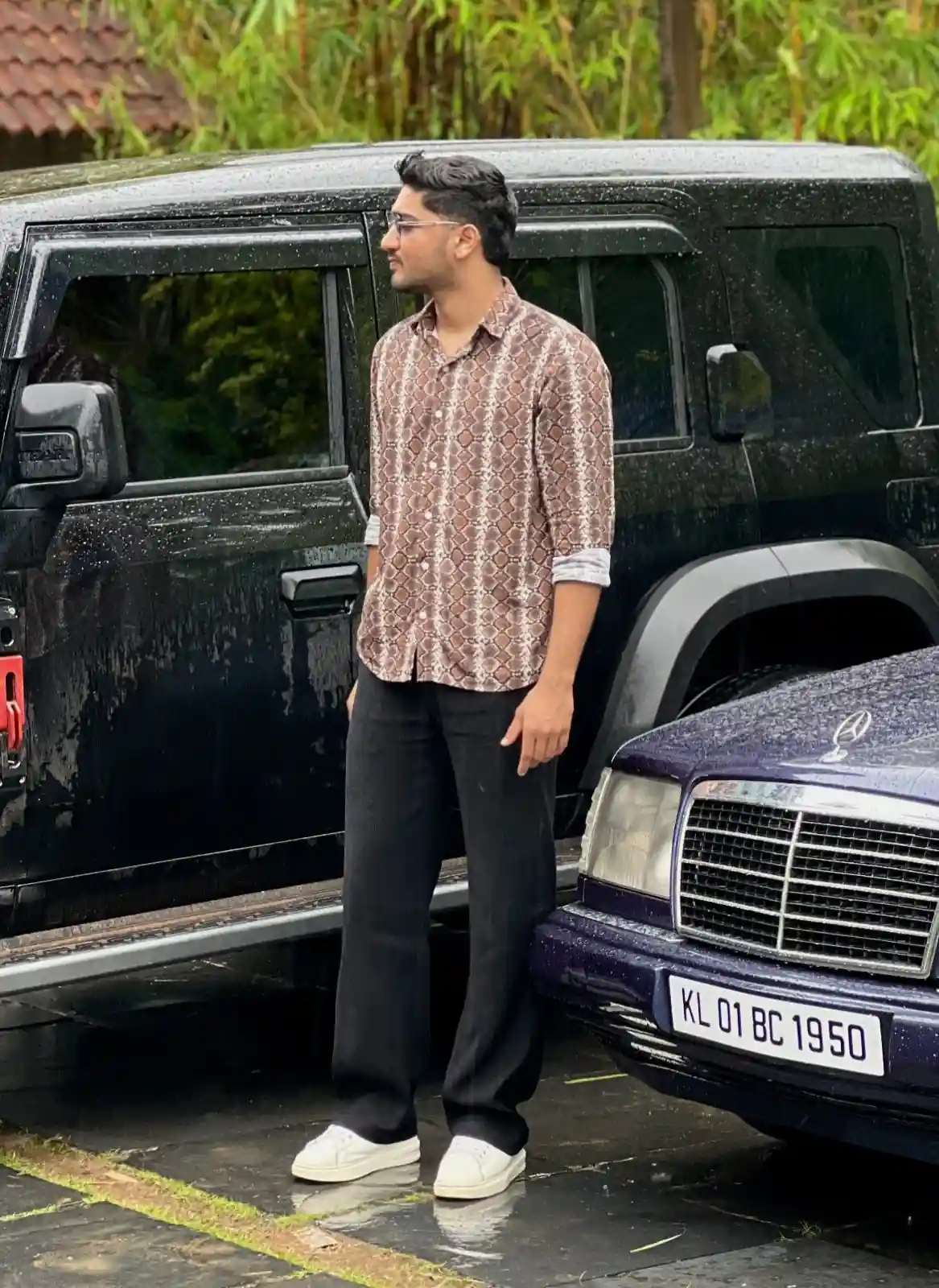 Portrait of a satisfied client standing outdoors beside two parked vehicles, featured in a testimonial for a Digital Marketing Consultant in Bahrain.